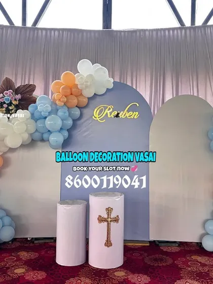 This naming ceremony setup was for a Christian event, featuring a cross symbol on a pedestal. The blue, orange, and white balloon arches create a bright and joyful atmosphere for the celebration.