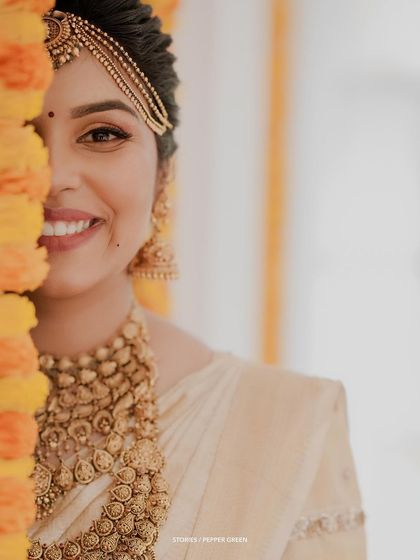 An artistic close-up of the bride's smiling face, partially hidden by a marigold garland.