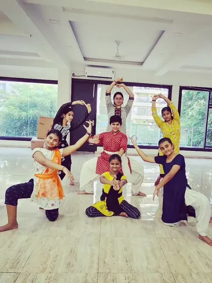 A group of adult learners striking a pose during their Bharatanatyam class. Our classes are a space for expression, fitness, and cultural connection for adults as well.