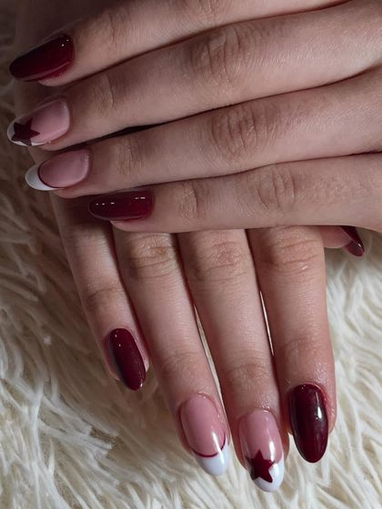 A bold and fierce design with red nail extensions. The accent nails feature a modern twist on a French manicure with a star cut-out design.