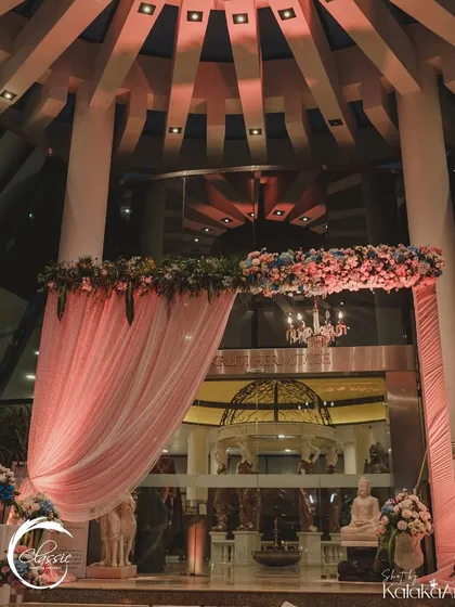Continuing the welcome inside, this archway with pink draping and a floral header frames the view into the hotel's grand lobby, connecting the outdoor and indoor decor.