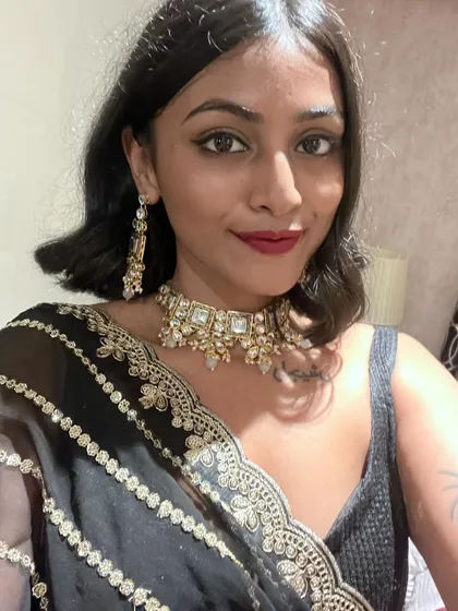 A close-up of my makeup and jewelry for the wedding. The bold red lip and the traditional choker set add a touch of glamour to the black saree.