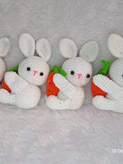 A row of sweet little white bunnies, each hugging a carrot.