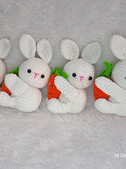 A row of sweet little white bunnies, each hugging a carrot.