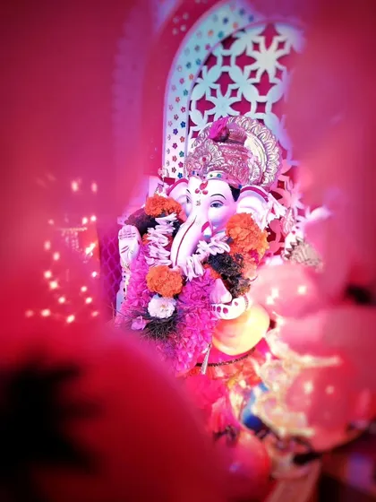 A creative, low light shot of a Ganesh idol in Pune, captured with a dreamy, soft focus effect. The vibrant pink lighting creates a unique and artistic feel for the festival.