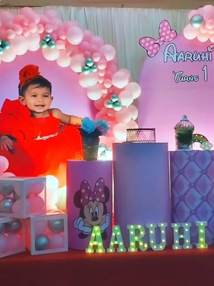 A classic Minnie Mouse first birthday party in vibrant pink. The backdrop features a large photo of the birthday girl, framed by a pink balloon arch and accented with Minnie Mouse props.