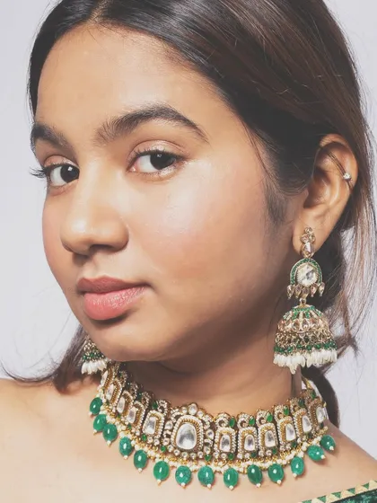 A close-up portrait focusing on the model's expression and the beautiful ethnic jewelry. The lighting is set up to highlight the details of the Kundan choker and jhumkas.