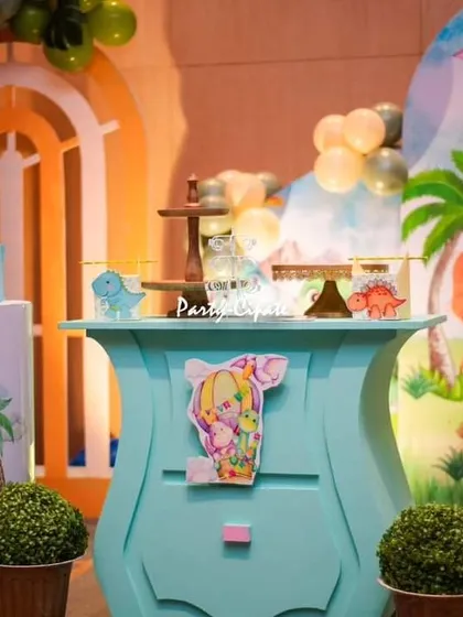 A closer look at the dessert table, showing the themed cake stands and the detailed backdrop with flying pterodactyls.