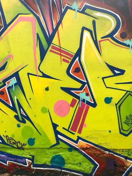 A close-up shot of the graffiti lettering. You can see the details of the spray can work, including the clean lines, color fades, and graphic elements like dots and highlights.