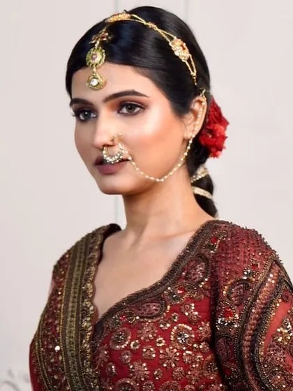 This angle highlights the soft, diffused bronze eyeshadow and the clean hairstyle, adorned with a single red rose for a touch of classic romance.