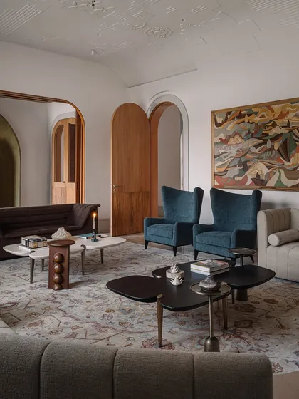 The ceiling of this formal living room is adorned with jewel-like light fixtures that resemble blooming flowers. These intricate, sculptural lights create a canopy of art, complementing the custom gypsum embroidery on the ceiling.