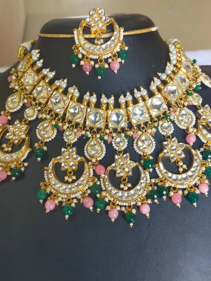 This is a perfect example of a classic bridal Kundan set. The combination of large, uncut stones with pink and green beads creates a timeless and regal look, available to rent for your wedding.