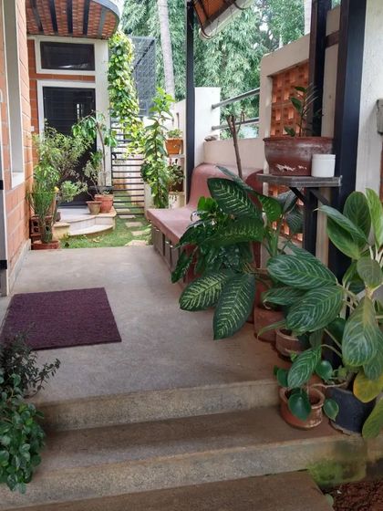 A cozy, plant-filled verandah space, perfect for enjoying a cup of tea while being protected from the elements.