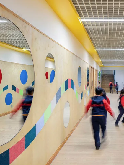 Students walking down a corridor with a dynamic, colorful wall design at GD Goenka Public School. The motion blur captures the energy of the space, which is designed to be more than just a simple passageway.