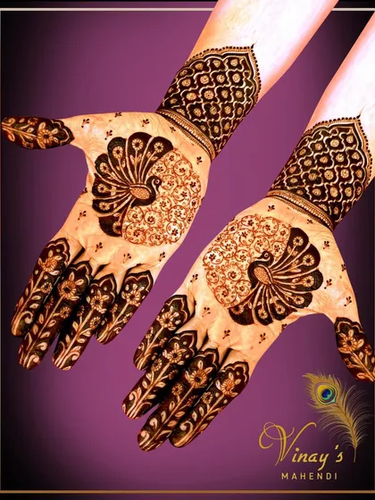 A striking back-of-hand design using negative space to highlight a beautiful peacock motif. The finger designs mimic floral vines.