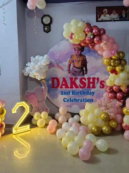 A personalized second birthday celebration with a custom photo backdrop and a pink, cream, and gold balloon arch.