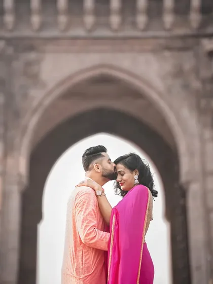A tender forehead kiss with the Gateway of India creating a perfect arch in the background. An iconic and romantic Mumbai pre-wedding photo.