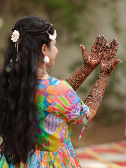 A candid shot of a bride dancing and showing the back of her hands, covered in beautiful henna.