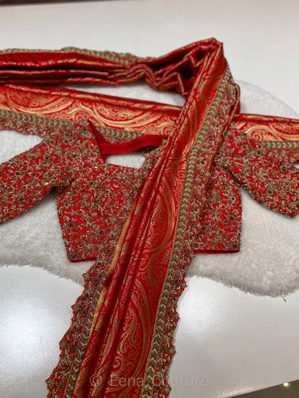 The beauty of a bridal trousseau lies in its details. This ensemble features a fully handworked red blouse with zardozi and sequin detailing, paired with a rich Banarasi dupatta that has an ornate paisley weave, making it a true heirloom piece.
