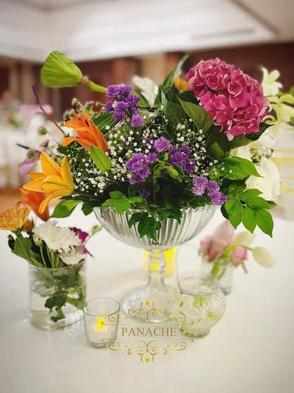 A beautiful centerpiece featuring a mix of purple, orange, and white flowers in a crystal vase.