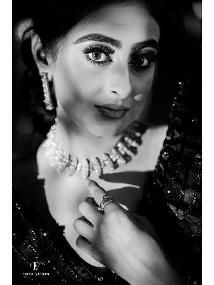 An intense and striking black and white close-up of the bride, with dramatic lighting highlighting her beautiful eyes and jewelry.