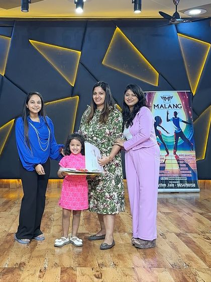 A young girl in a pink dress smiles as she receives her certificate and art supplies. We celebrate every child's unique journey and participation, ensuring they leave with happy memories and a feeling of pride.