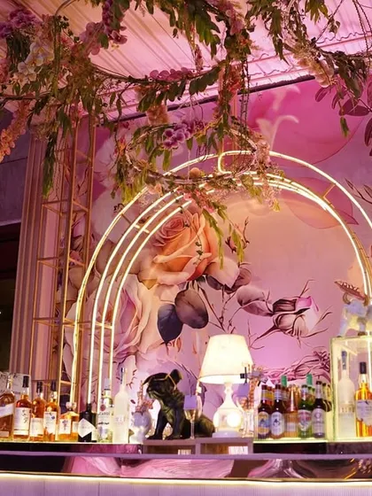 I designed this bar to be a whimsical floral fantasy. A hand-painted backdrop, glowing arches, and a canopy of hanging flowers created a truly enchanting space for cocktails.