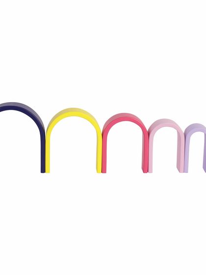 The separate pieces of a wooden pastel arch toy, arranged to show the different sizes and colors.