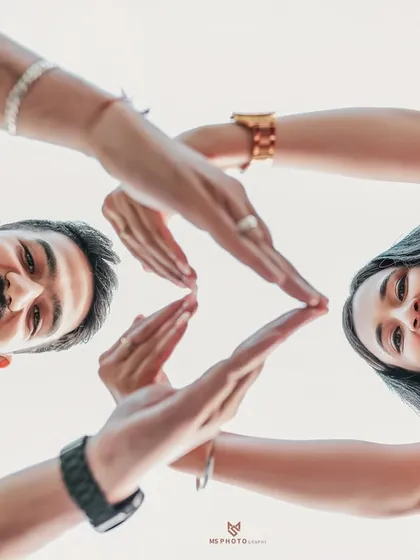 A fun and creative low-angle shot of a couple making a heart shape with their hands. It’s a playful and unique portrait.