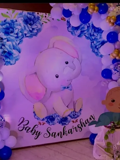 For this baby welcome party, I designed a custom backdrop featuring a cute baby elephant illustration. The theme was completed with a blue and white balloon garland arch framing the backdrop for "Baby Sankarshan".