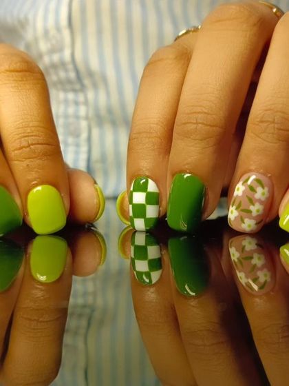 A playful green manicure with checkerboard and floral accent nails.