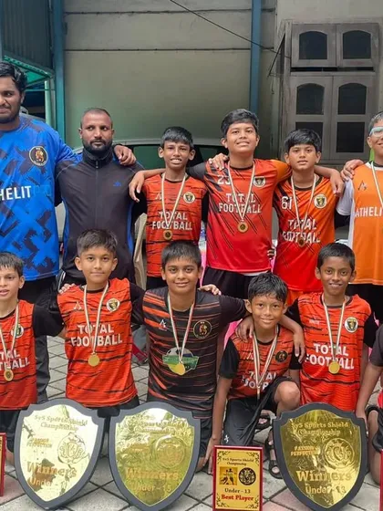 Players and coaches together celebrating a massive haul of trophies from the 5v5 Sports tournament.