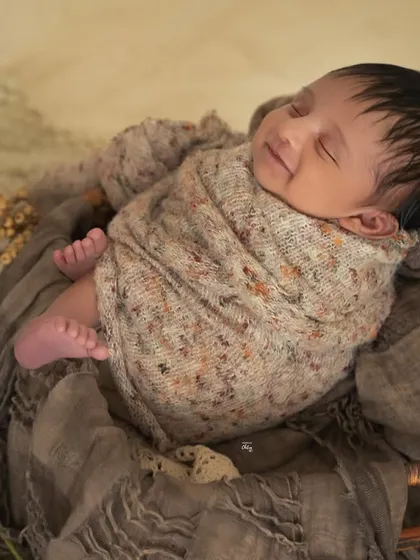A side view showing the baby's peaceful profile and tiny feet, all wrapped up in a knitted swaddle.