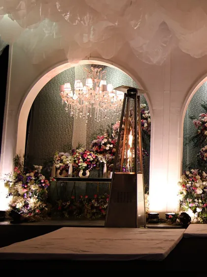 A stage setup with floral-filled arches and crystal chandeliers, creating a beautiful backdrop for performances or speeches.