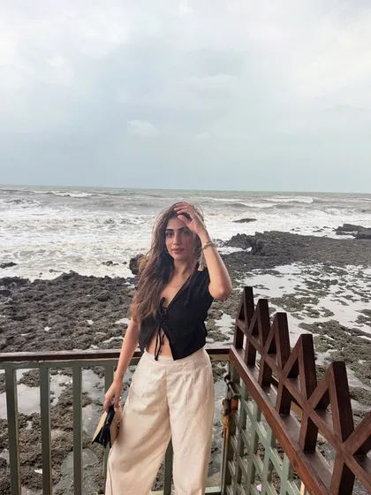 An unbothered moment by the sea in Goa. I’m wearing a black tie-front top with cream-colored wide-leg pants, a classic beach vacation combo.