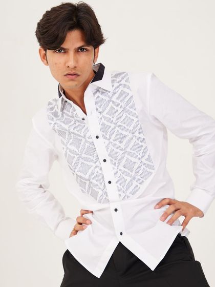 This crisp white shirt features a bib with an intricate geometric pattern created through pintucks and embroidery. The contrasting black collar and buttons add a formal, modern touch.