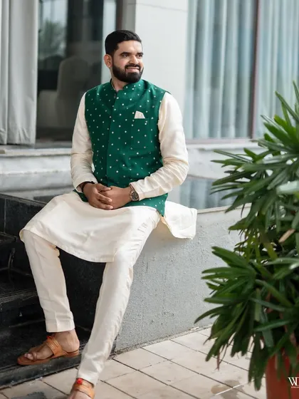 Groom styling is about confidence and personality. Here, the groom looks sharp and relaxed in a classic off-white kurta set paired with a stylish green mirror-work Nehru jacket, a perfect outfit for an engagement or sangeet ceremony.