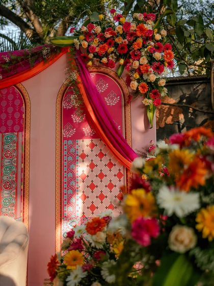 The interplay of sunlight and shadow highlights the intricate details of the floral bouquets and the printed backdrop, creating a warm and inviting atmosphere.