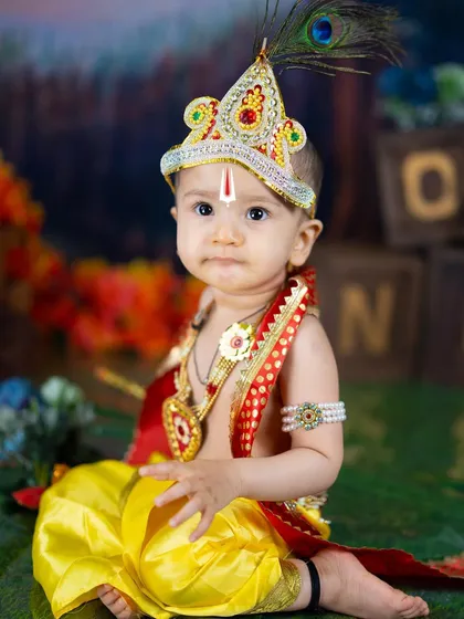 A calm and serene portrait of a baby boy dressed as Lord Krishna. The traditional jewelry and tilak complete this divine look.