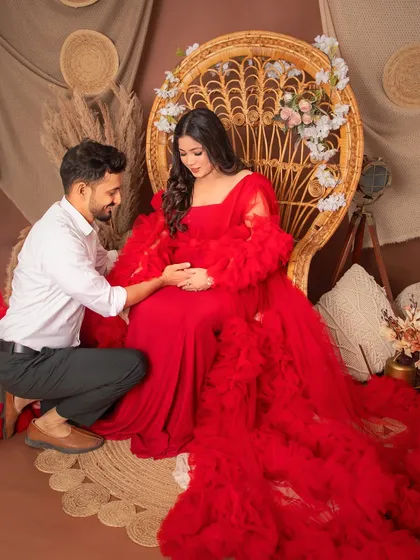 A tender moment between partners in our boho-themed studio setup. The vibrant red ruffled gown adds a touch of drama and romance, perfectly capturing the love and excitement of waiting for your little one.