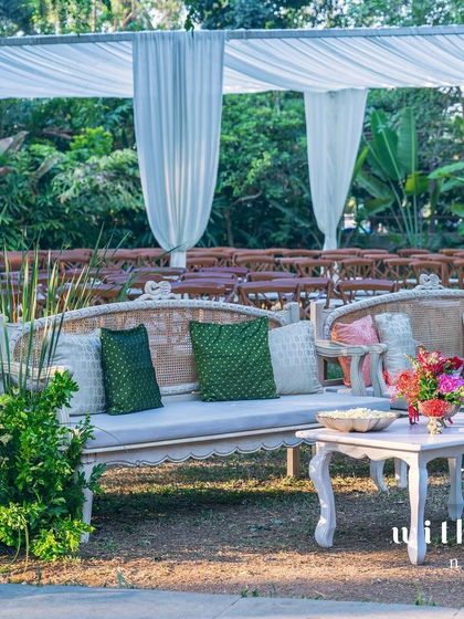 A comfortable lounge area for guests at a summer wedding, with classic furniture and colorful cushions.