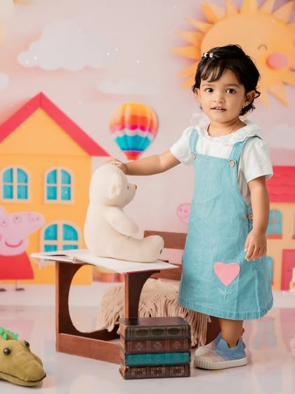 Standing with her teddy bear friend in the world of Peppa Pig.