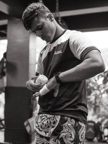 A fighter in black and white wraps his hands, a timeless image of preparation.