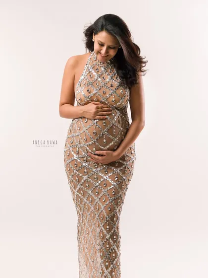 A full-length view of the sheer jeweled gown. This portrait captures the intricate details and the mother's serene confidence.