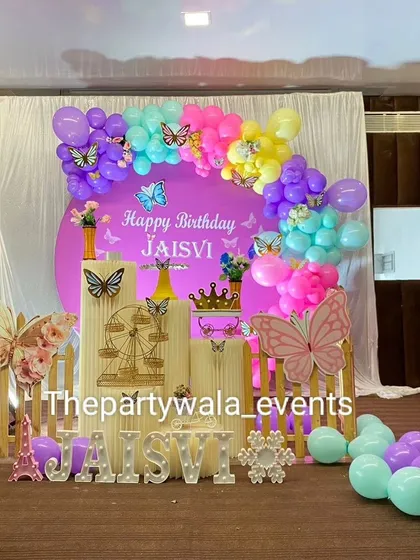 A bright and colorful butterfly theme with a purple backdrop. The mix of purple, yellow, pink, and aqua balloons creates a very playful and eye-catching display.