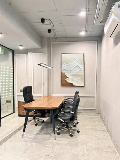 A smaller meeting room or cabin, designed with classic wall molding and modern art. The space is simple, elegant, and functional, providing a quiet area for focused work or discussions.