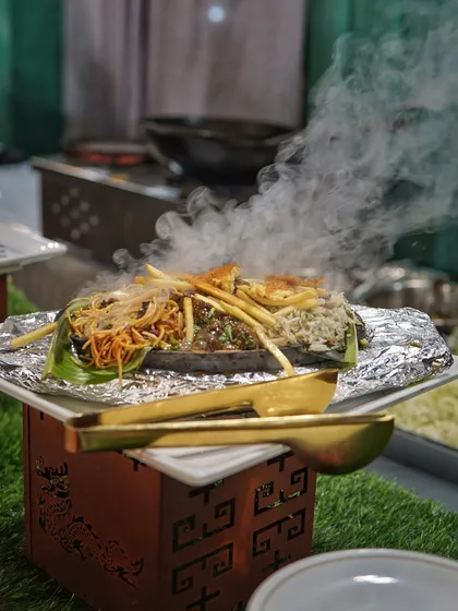 Nothing beats the sound and aroma of a sizzling platter. Here, a freshly prepared dish is served on a hot plate, creating a dramatic cloud of steam.
