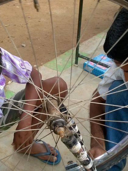 Two boys work together to fix a bicycle wheel. Our workshops encourage teamwork and peer to peer learning, creating a fun and supportive environment for everyone involved.