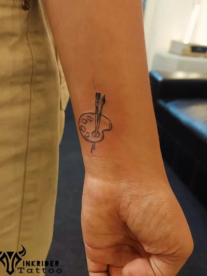 For the artist at heart, a minimalist paint palette and brushes. This fine-line wrist tattoo is a perfect tribute to a creative passion.