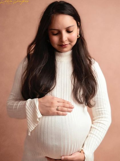 A solo portrait of the mom-to-be, looking down at her bump with so much love. The simple white dress and soft background create a timeless image.